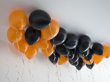 bunch of orange and black air balloons for halloween or birthday over white ceiling background. Holidays, decoration and party concept.