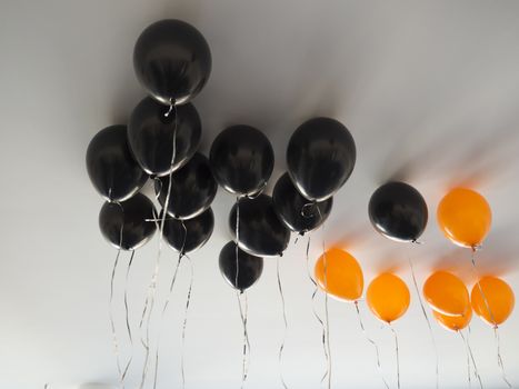 bunch of orange and black air balloons for halloween or birthday over white ceiling background. Holidays, decoration and party concept.