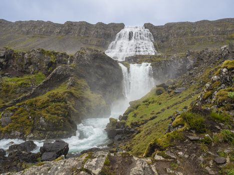 Dynjandi waterfall, biggest in west fjords of Iceland in summer, rock, mossed hills, river stream and blue sky background