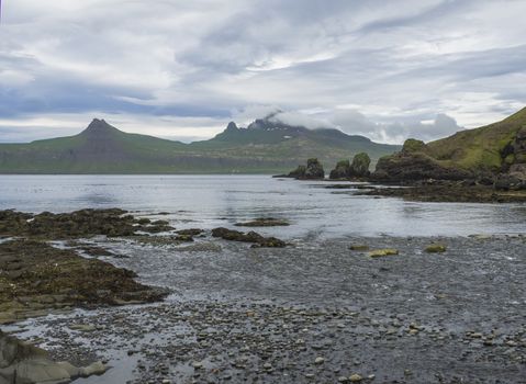 Scenic view on beautiful Hornbjarg cliffs in west fjords, remote nature reserve Hornstrandir in Iceland, rocky pebble coast with bird cliff rocks, sea and blue sky clouds background