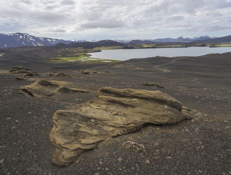 view on landscape with Colorful crater lake and volcanic snow covered mountains and dirty road in Veidivotn lakes, popular fishing area for local, central Iceland highlands in the middle of black lava desert