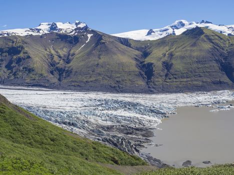 View on glacier lagoon with icebergs and tongue of Skaftafellsjokull, Vatnajokull spur and colorful snow covered rhyolit mountains in Skaftafell national park, Iceland