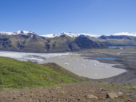 View on glacier lagoon with icebergs and tongue of Skaftafellsjokull, Vatnajokull spur, valley Morsardalur river and colorful rhyolit mountains in Skaftafell national park, Iceland