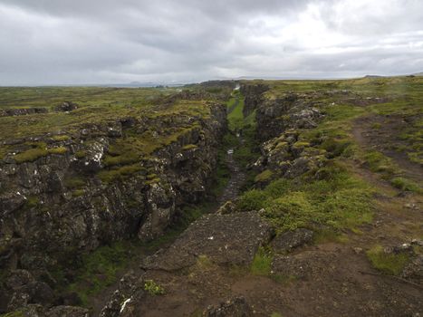 View on north american - europe lithosferic rift - Mid-Atlantic Ridge in Thingvellir national park, Iceland with foot path and walking tourist people