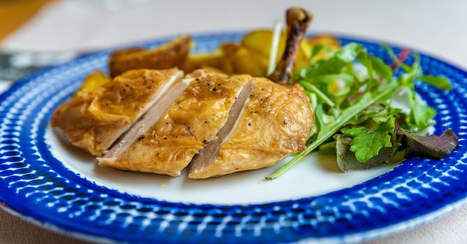 roasted chicken leg on a plate, close-up.
