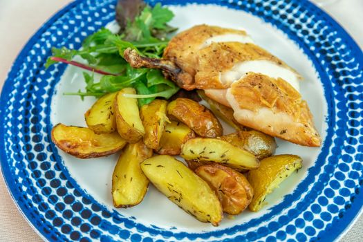 roasted chicken leg with potatoes on a plate in a restaurant.