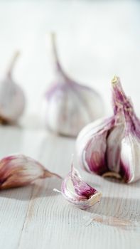 Garlic bulb with garlic cloves on white wooden background. Perfect garlic with copy space for text or design. Vertical. Shallow DOF