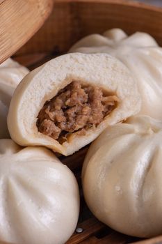 Delicious baozi, Chinese steamed meat bun is ready to eat on serving plate and steamer, close up, copy space product design concept.