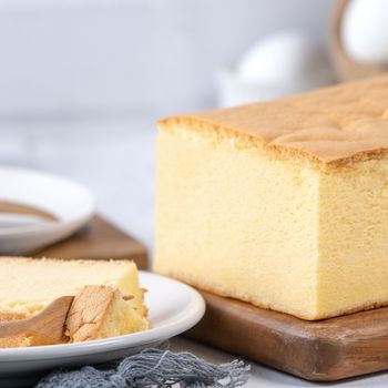 Plain classic Taiwanese traditional sponge cake (Taiwanese castella kasutera) on a wooden tray background table with ingredients, close up.