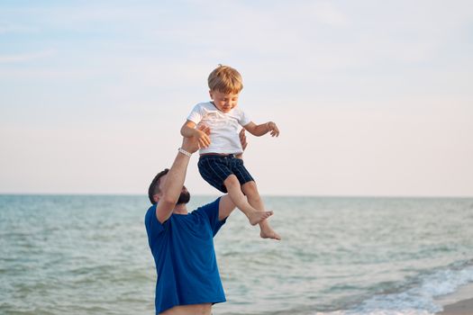 Father throwing son spending time together sea vacation Young dad child little boy walking beach Fathers day. Family with one child. Happy childhood with daddy.