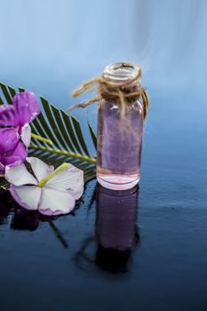 Herbal and floral essence or concentration made from Rosmarinus officinalis also known as rosemarry flower in a glass bottle on wooden surface.