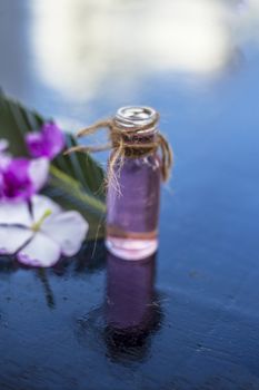 Herbal and floral essence or concentration made from Rosmarinus officinalis also known as rosemarry flower in a glass bottle on wooden surface.