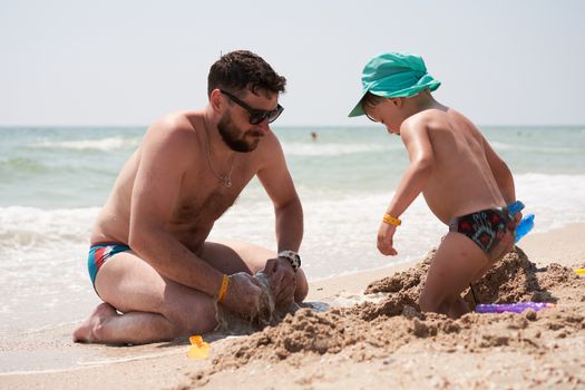 Father son together summer vacation playing sand sea beach Dad kid enjoyment togetherness weekend activity. Family with one child lifestyle. Caucasian male play