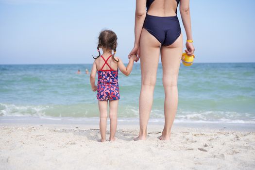 Mother daughter beach together rear view Unrecognizable caucasian woman little girl swimwear standing seaside back Family with one child. Family Vacation Summertime