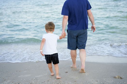 Dad holds son hand. Father Child spending time together sea vacation Young man little boy walking beach Fathers day. Family with one child. Happy childhood with daddy.