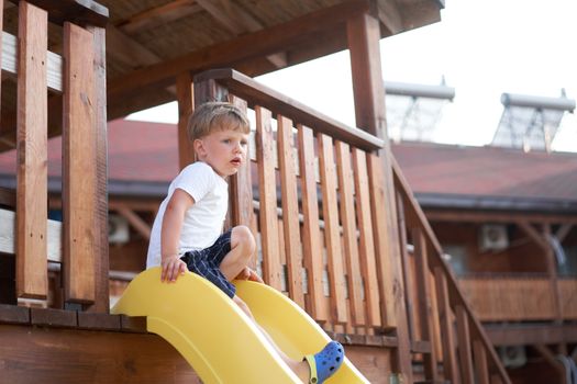 Little boy slide playing playground Active childhood Enjoy summertime Caucasian kid have fun outdoor. Summer holidays