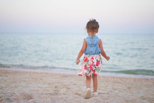 Child playing sand beach Little girl play sad alone summer family vacation Caucasian female 3 years old dressed denim near sea water