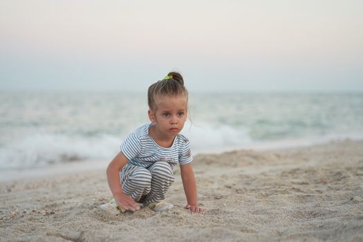 Child playing sand beach Little girl play sad alone summer family vacation Caucasian female 3 years old dressed denim near sea water