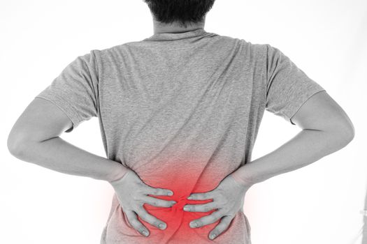 Black and white shot of man feeling exhausted and suffering from waist and back pain and injury on isolated white background with red spot. Health care and medical concept.