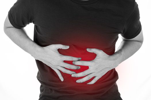 Black and white shot of man feeling exhausted and suffering from stomach pain and injury on isolated white background with red spot. Health care and medical concept.