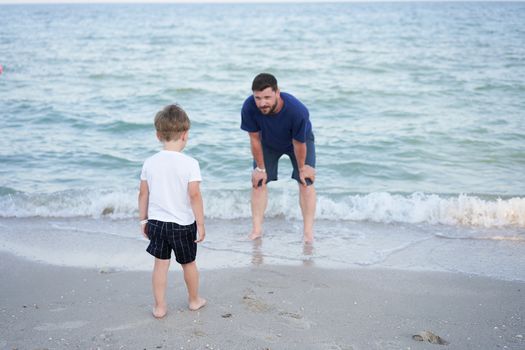 Dad holds son hand. Father Child spending time together sea vacation Young man little boy walking beach Fathers day. Family with one child. Happy childhood with daddy. Full lenght
