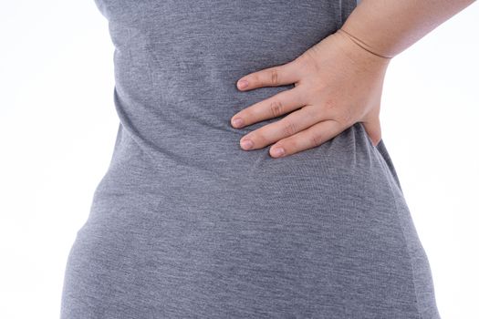 A woman feeling exhausted and suffering from waist and back pain and injury on isolated white background. Health care and medical concept.