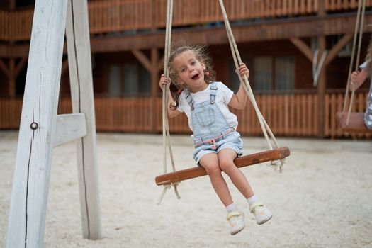 Playful kid swinging swing. Joyful little girl play having fun playground summertime Enjoyment outside. Summer children leisure. Preschool lifestyle