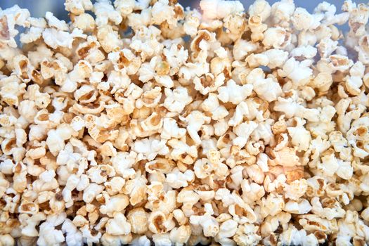 Popcorn background behind glass in a po pcorn maker. Abstract food texture. Eating for cinema