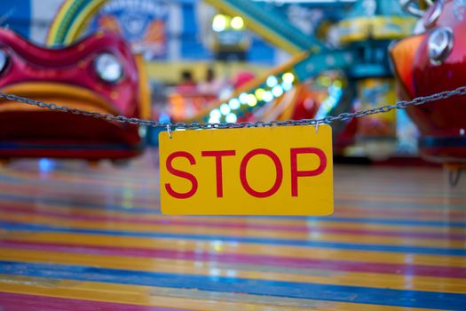 Stop sign with carnival festival blurred Carousel background Amusement park closed quarantine. Accident entertainment park. Nightlife holiday vacation