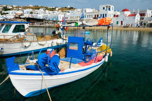 Greek fishing boat in clear sea water in port of Mykonos. Chora town, Mykonos, Greece