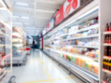 Supermarket blur background. Blurred interior view with walkway between cold drink beverage product shelves in shopping mall.