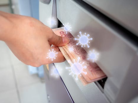 Hand picking banknote from ATM machine with virus floating around. Virus infection spread disease concept.