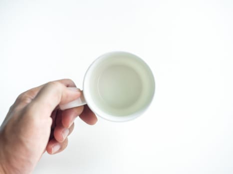 Empty white clean ceramic coffee cup in hand isolated on white background, top view. Hand holding blank round cup.