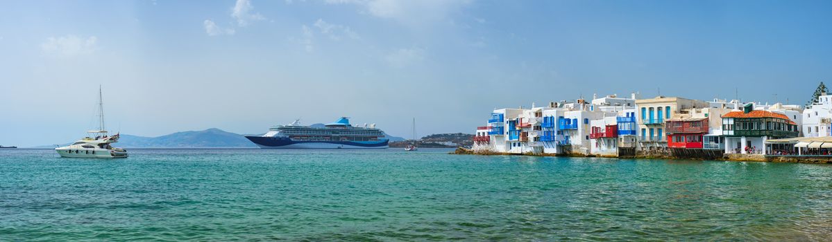 Scenic Little Venice houses in Chora Mykonos town with yacht and cruise ship. Mykonos island, Greecer