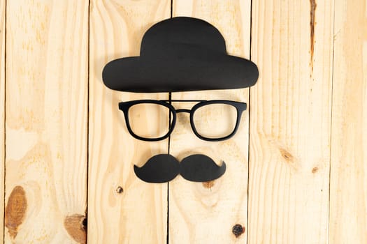 Happy Father Day background concept with glasses, black hat and black mustache on wooden background with copy space for text.