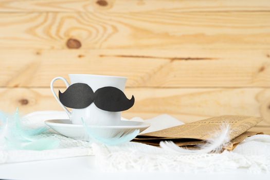 Happy Father Day background concept with and cup of tea, black mustache and newspaper on wooden background with copy space for text.