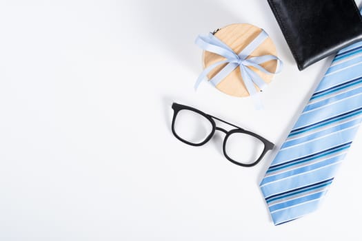 Happy Father Day background concept with blue necktie, glasses, wallet and gift box on white background with copy space for text.