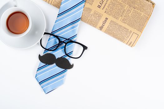 Happy Father Day background concept with blue necktie, glasses, cup of tea, newspaper and black mustache on white background with copy space for text.