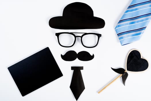 Happy Father Day background concept with blue necktie and paper cut of hat, glasses, black mustache, necktie, heart shape and blackboard on white background with copy space for text.
