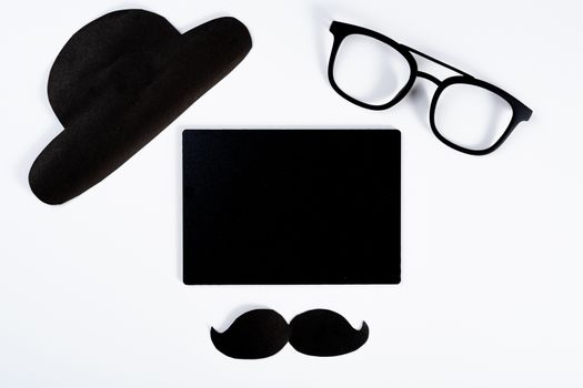 Happy Father Day background concept with blackboard and paper cut of hat, glasses and black mustache on white background with copy space for text.