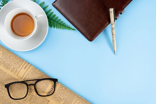 Happy Father Day background concept with notebook, pen, leaf, cup of tea, glasses and newspaper on blue background with copy space for text.
