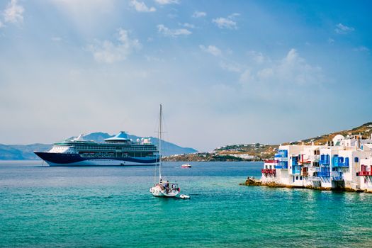 Scenic Little Venice houses in Chora Mykonos town with yacht and cruise ship. Mykonos island, Greecer