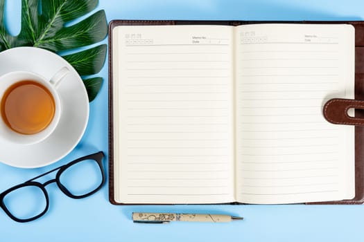 Happy Father Day background concept with notebook, pen, leaf, cup of tea and glasses on blue background with copy space for text.