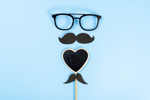 Happy Father Day background concept with glasses, black heart shape and black mustache on blue background with copy space for text.