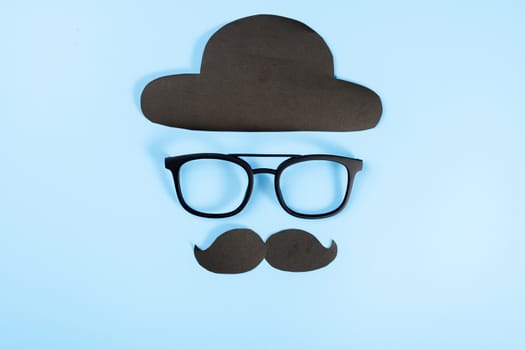 Happy Father Day background concept with glasses, black hat and black mustache on blue background with copy space for text.