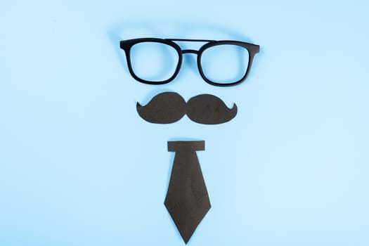 Happy Father Day background concept with glasses, black tie and black mustache on blue background with copy space for text.
