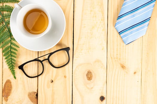 Happy Father Day background concept with blue necktie, glasses and cup of tea on wooden background with copy space for text.