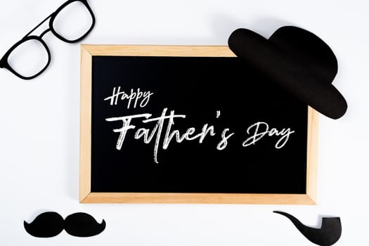 Happy Father Day background concept with blackboard and paper cut of hat, glasses, black mustache and smoking pipe on white background with copy space for text.