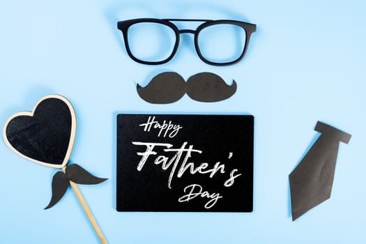 Happy Father Day background concept with glasses, blackboard, black heart shape, tie and black mustache on blue background with copy space for text.