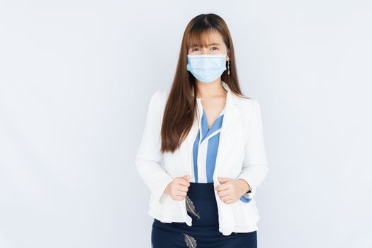 Smiling Asian business woman wearing a medical face mask and looking at the camera the over grey background. Back to the normal concept.